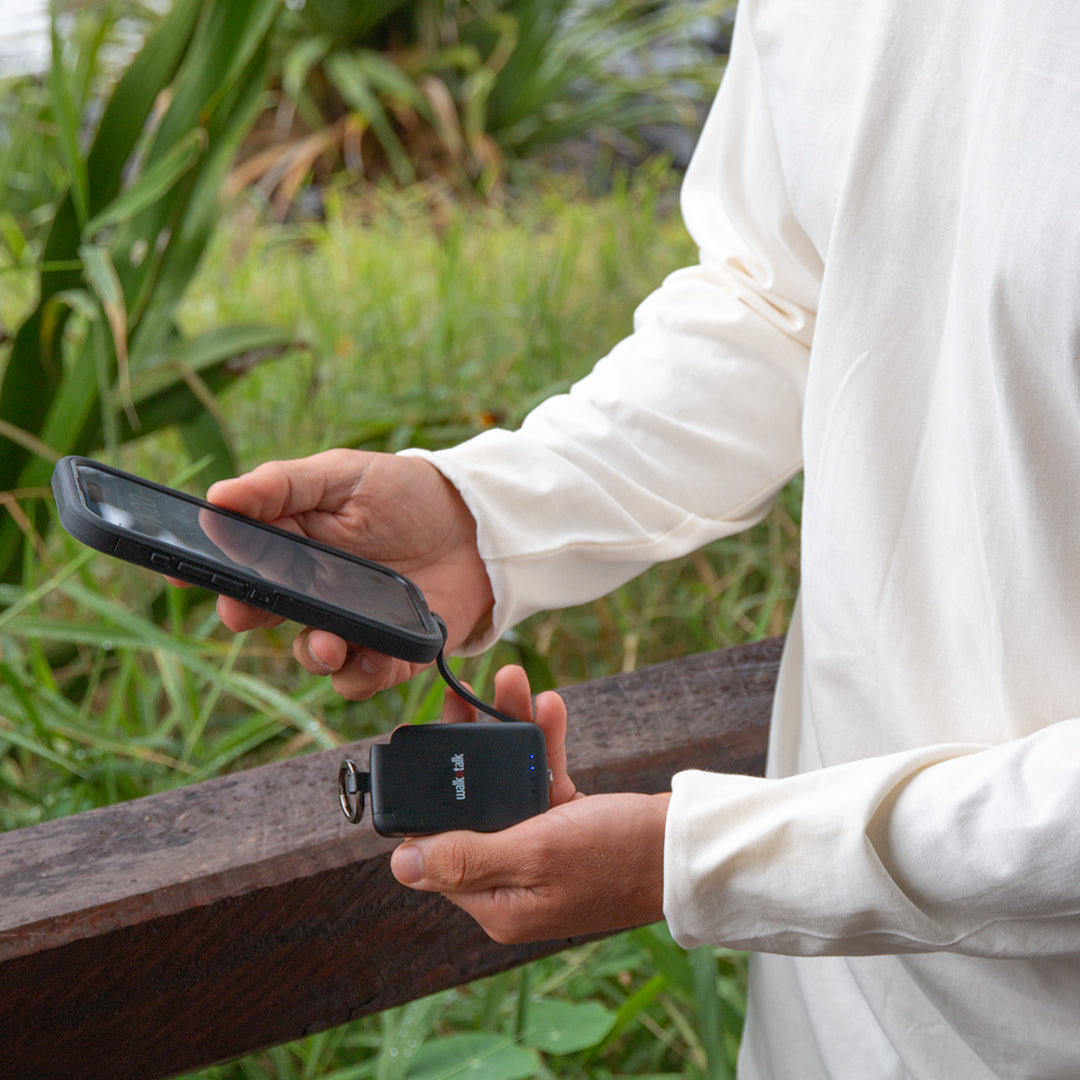 Man charging a phone with his Black Emergency Mini Power Bank Keychain