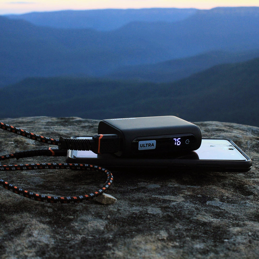 Ultra 10K Power Bank charging a phone on a mountain