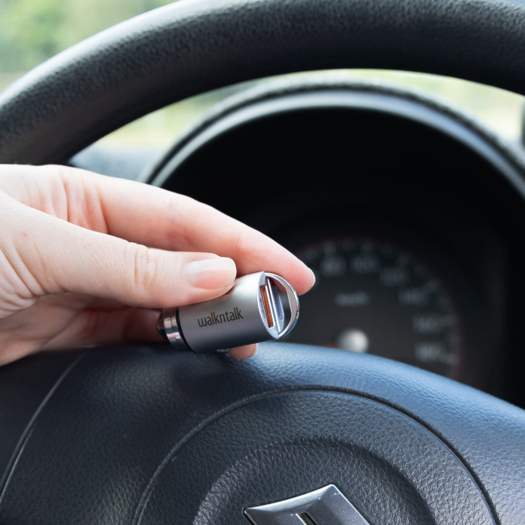 Woman holding a silver Mini Dual USB Car Charger in a car